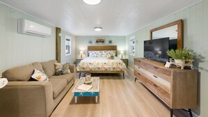 A bedroom with a bed, a wooden dresser, a sofa, and a coffee table. - Salt and Sand Studio (Downstairs Only) (Panama City Beach)