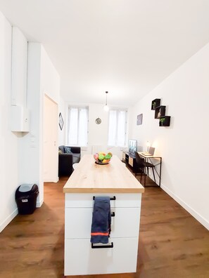 Une cuisine moderne dotée d’un îlot central, un coin repas avec une table et des chaises, et un espace de vie comprenant un canapé et une table basse.