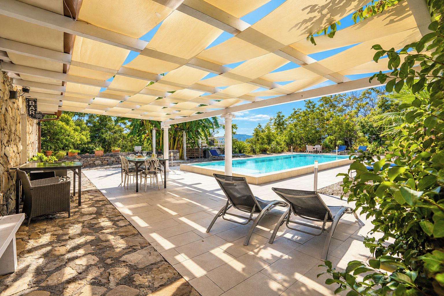 A covered outdoor area with a pool, seating, and a table.