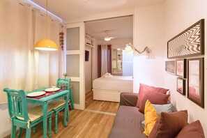 A compact room with a dining table, chairs, a sofa, and a bed.