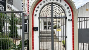 Una entrada con portón a un edificio con un cartel que dice "MANHATTAN'S HOME" y el número "164" en el portón.