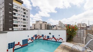 Una piscina en la azotea con paredes de azulejos y vistas de edificios circundantes.