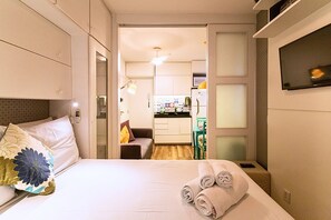A hotel room with a bed, a desk, and a kitchenette.