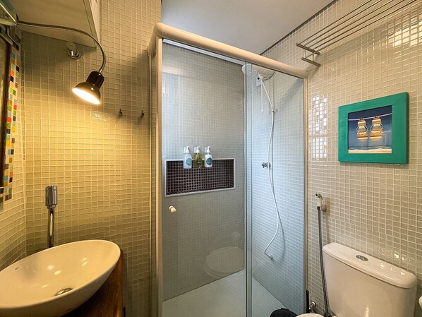 A bathroom with a glass-enclosed shower, a sink, and a toilet.