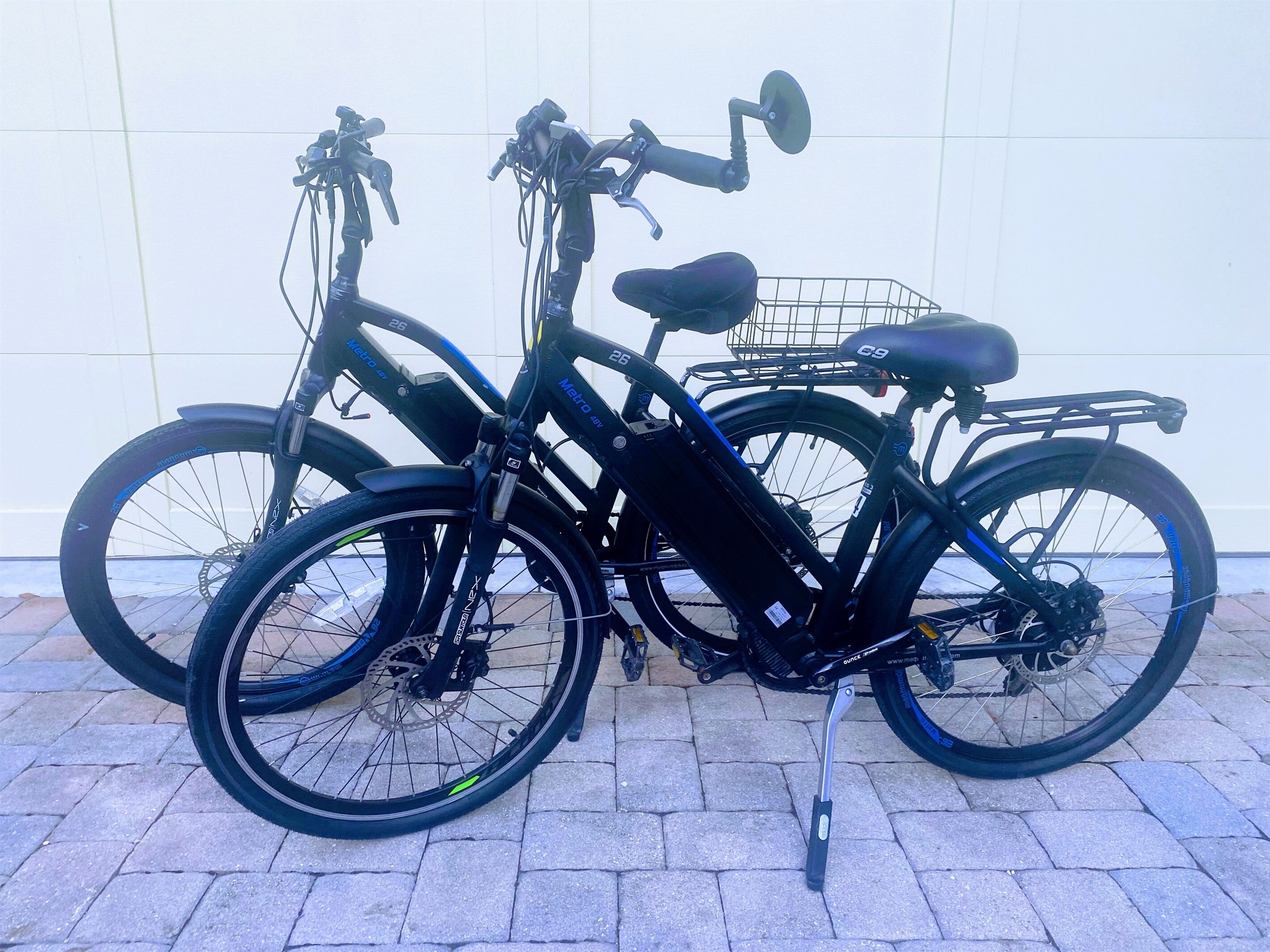 Two bicycles parked against a white wall.