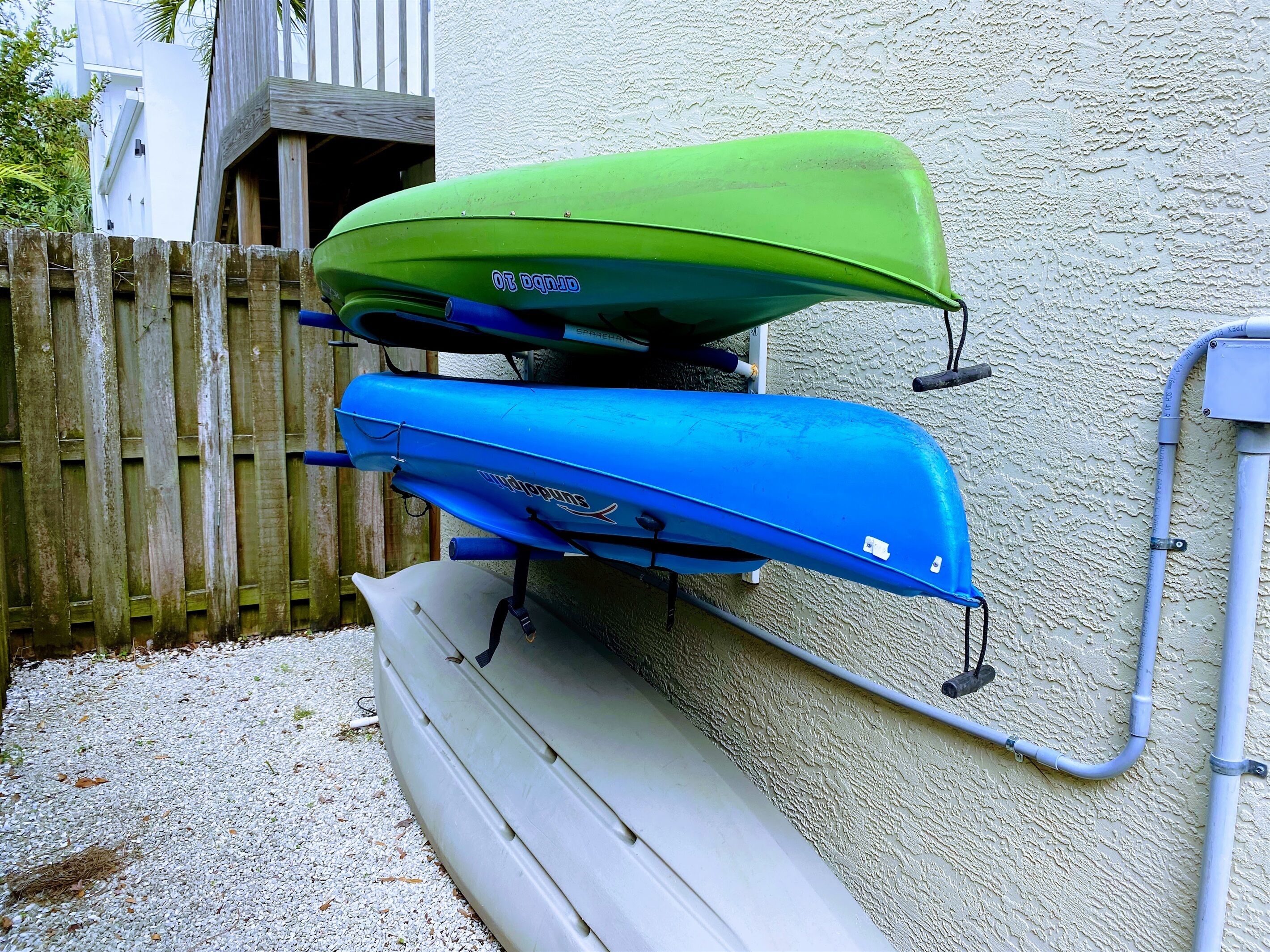 Two kayaks, one green and one blue, mounted on a wall.