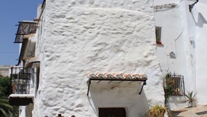 Un edificio bianco con facciata in pietra, una porta in legno e una pompa d'acqua in metallo.