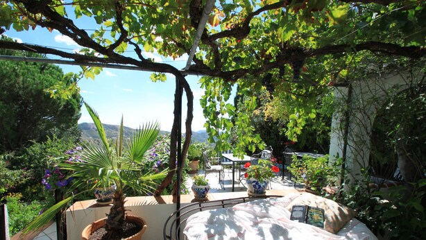 Patio giardino con un letto, piante in vaso e vista sul paesaggio.
