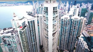 A high-rise building with multiple balconies and a view of a body of water.