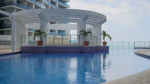 A modern hotel pool with a clear blue water feature, surrounded by a white structure with balconies.