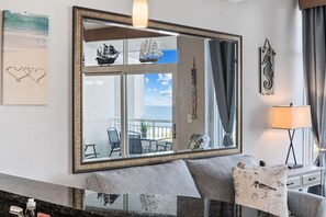 A living room with a large mirror reflecting a balcony with chairs and a ship model. - Escape to an Ocean View, Indoor and outdoor Resort Amenities (Myrtle Beach)