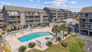 A multi-story hotel with a central swimming pool, balconies, and palm trees. - 3rd Floor Ocean View, Pools/Hot Tub- Shore Dr (Myrtle Beach)