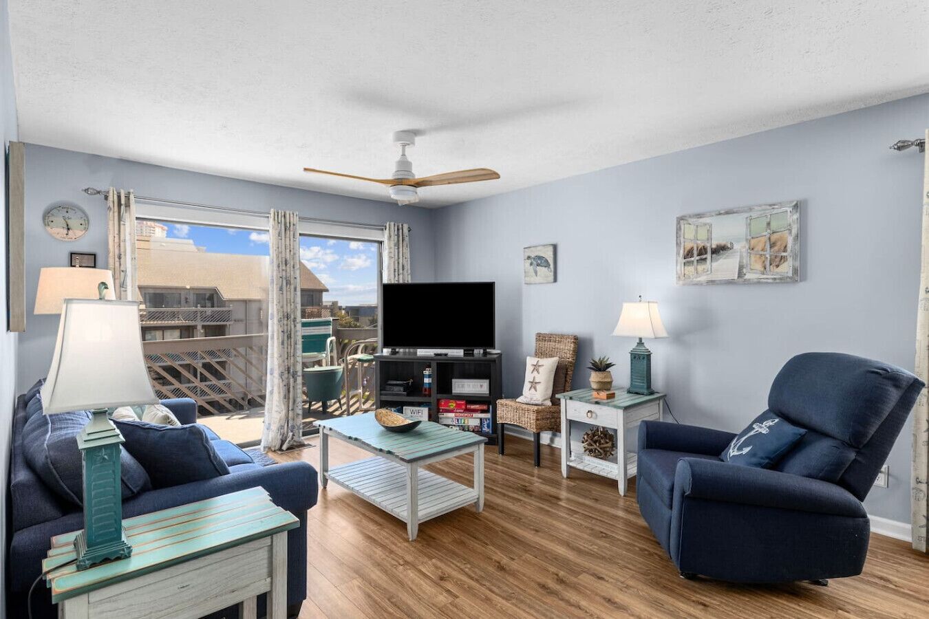 A living room with a TV, two armchairs, a coffee table, and a ceiling fan.