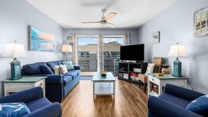 A living room with a sofa set, a coffee table, a TV, and a ceiling fan. - 3rd Floor Ocean View, Pools/Hot Tub- Shore Dr (Myrtle Beach)