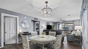 Een moderne woonkamer met een ronde glazen tafel, comfortabele zitplaatsen, een plafondventilator en uitzicht op de stad.