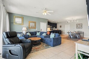 A living room with a sofa, chairs, a coffee table, and a ceiling fan.