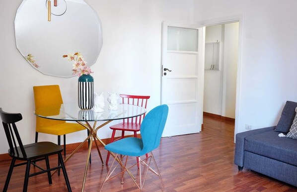 A dining area with a glass table, chairs, and a vase of flowers.