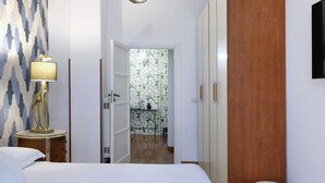 Habitación de hotel con cama, lámpara, armario y vistas al baño con ducha.