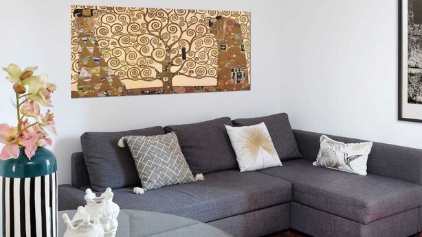 Una sala moderna con un sofá seccional gris, una mesa de centro de vidrio y un adorno de pared decorativo.