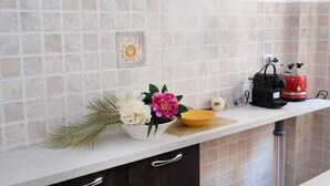 Una cocina con encimera blanca, un tostador rojo, un bol y un salpicadero decorativo de azulejos.