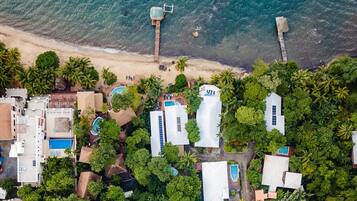 Vista aèria d'una estació turística costanera amb diversos edificis, piscines i una platja.