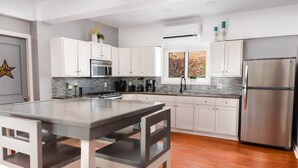 Una cocina moderna con armarios blancos, un refrigerador de acero inoxidable, horno empotrado y una isla grande con sillas.