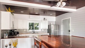 Una cocina moderna con armarios blancos, un refrigerador de acero inoxidable y una encimera de madera.