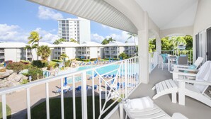 Ein Hotelbalkon mit Pool, Liegestühlen und Blick auf das Pool-Gelände.