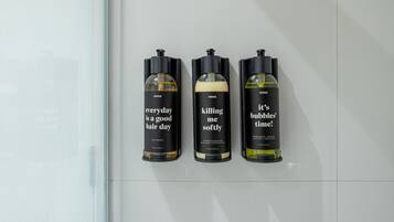 Three bottles of hair care products on a white tiled wall.