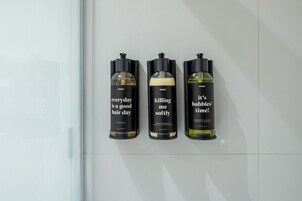 Three bottles of hair care products on a white tiled wall.