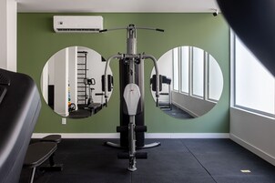 Un gimnasio con equipo de ejercicio, un espejo y una ventana.