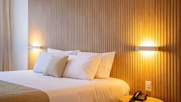 Ein Hotelzimmer mit einem großen Bett, weißer Bettwäsche und einem Nachttisch mit Telefon.