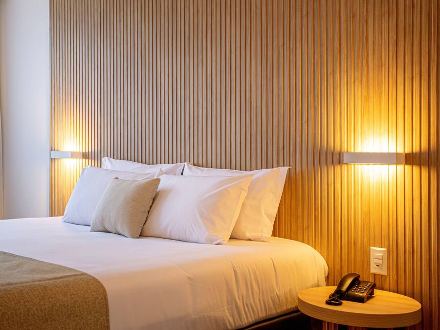 Ein Hotelzimmer mit einem großen Bett, weißer Bettwäsche und einem Nachttisch mit Telefon.