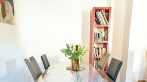 Une table de conférence entourée de chaises, une plante en pot et une bibliothèque en arrière-plan.