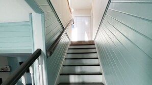 Eine Treppe mit weißen Geländern und dunklen Stufen führt zu einer Tür oben.