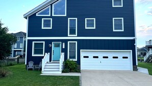 Ein zweistöckiges Haus mit Garage, einer Veranda mit Treppe und einer blauen Tür.