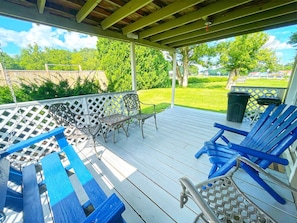 Un patio al aire libre techado con mobiliario de madera azul y blanco, incluyendo sillas y una mesa.