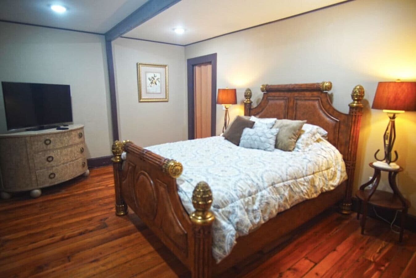 Un dormitorio con una cama de madera, un aparador, un televisor y dos lámparas.