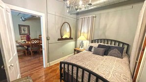 Une chambre à coucher avec un lit, une table de chevet, un miroir et un lustre.