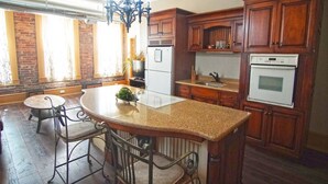 A kitchen with wooden cabinets, a granite countertop, a built-in oven, and a chandelier. - Shopping District Apt | Heart of Historic Downtown (Marietta)