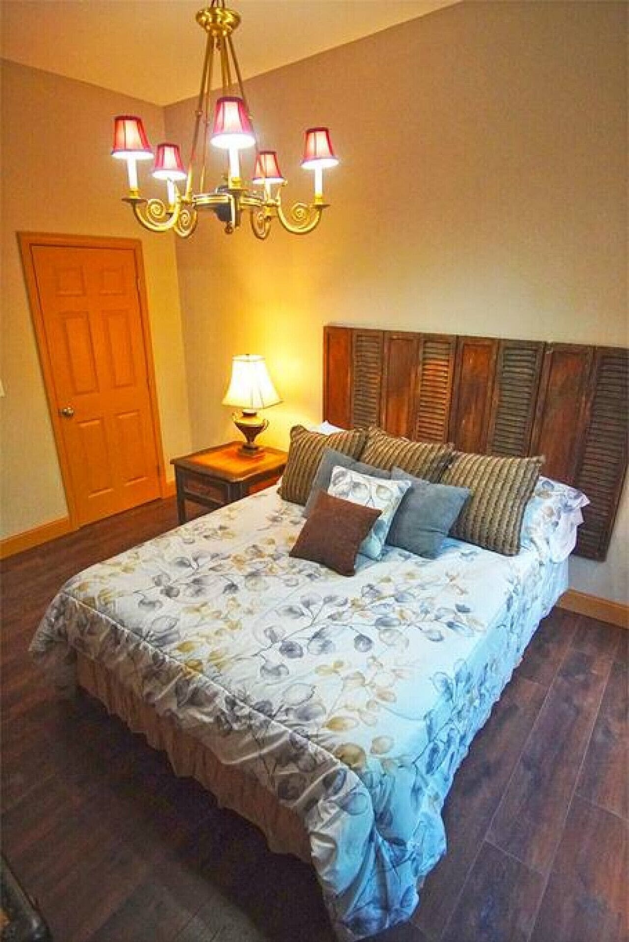 Une chambre à coucher avec un lit, une table de chevet, une lampe et un lustre.
