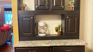 Una cocina de madera oscura con encimera de granito, armarios empotrados y una cafetera.