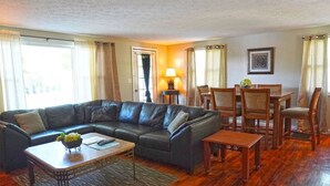 Ein Wohnzimmer mit Ledersofa, Couchtisch aus Holz und Esstisch.
