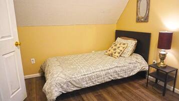A bedroom with a bed, a nightstand, a lamp, and a mirror on the wall.