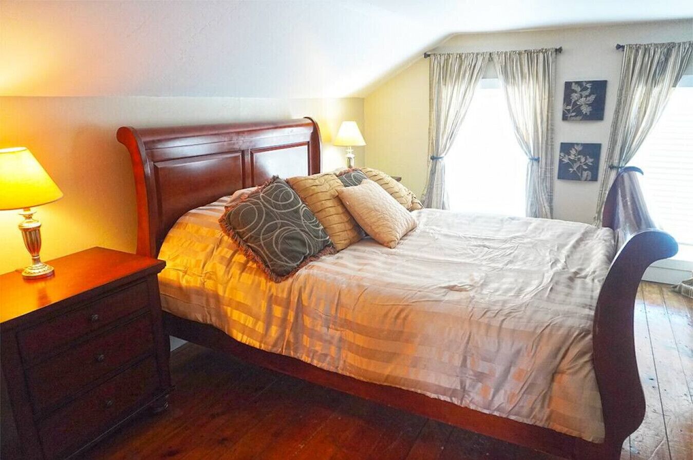 Un lit bien fait, avec une tête de lit en bois, une table de chevet avec une lampe et une fenêtre avec des rideaux.