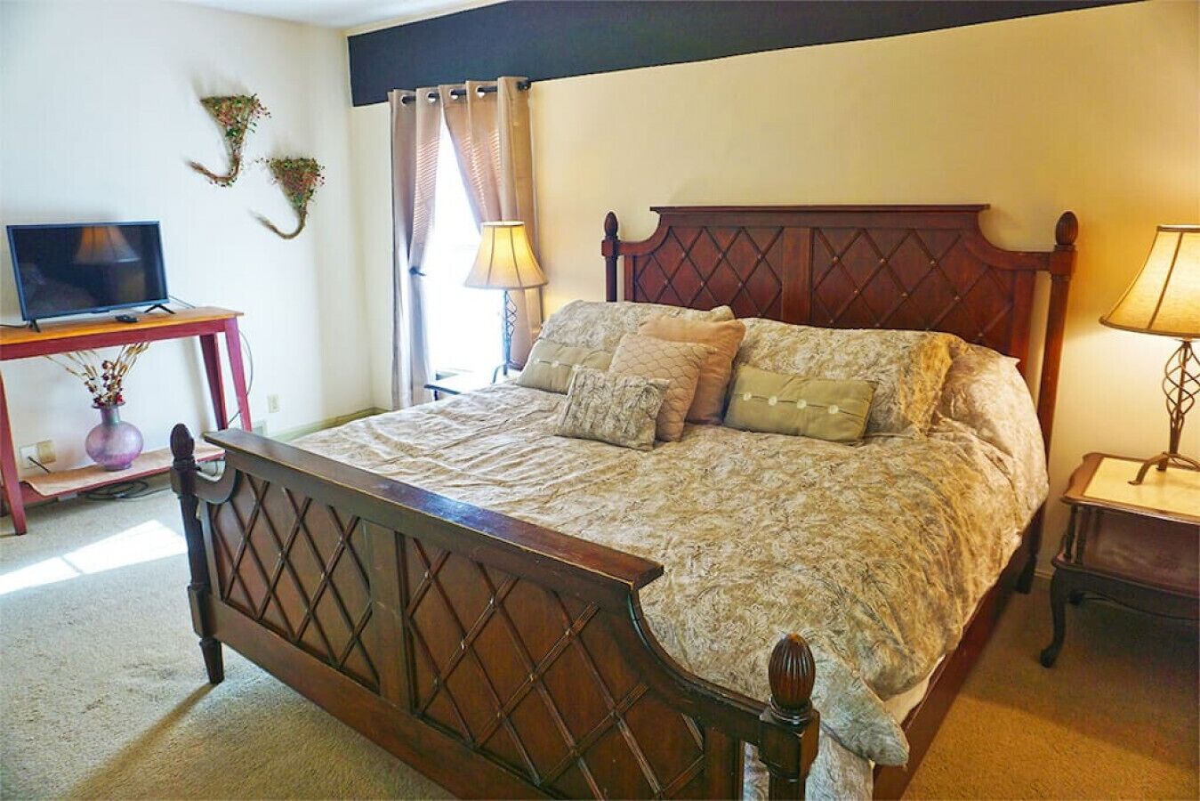 A bedroom with a wooden bed, a television on a stand, and a lamp on a nightstand.
