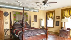 A four-poster bed with a wooden frame and a dark patterned bedspread. There is a ceiling fan above the bed, and a radiator on the wall. - Pearl`s Place in heart of Historic Roscoe Village (Coshocton)