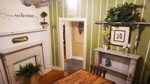 A cozy room with a fireplace, a dining table, and a shelf with decorative items. - Pearl`s Place in heart of Historic Roscoe Village (Coshocton)