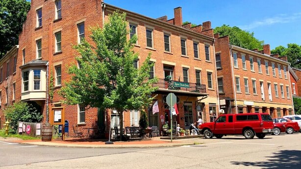 A brick building with a corner storefront, a red pickup truck parked in front, and a tree in the foreground. - Pearl`s Place in heart of Historic Roscoe Village (Coshocton)
