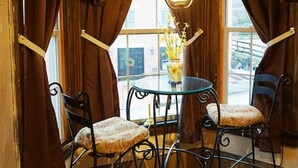 A corner room with a table and four chairs, large windows, and curtains. - Pearl`s Place in heart of Historic Roscoe Village (Coshocton)